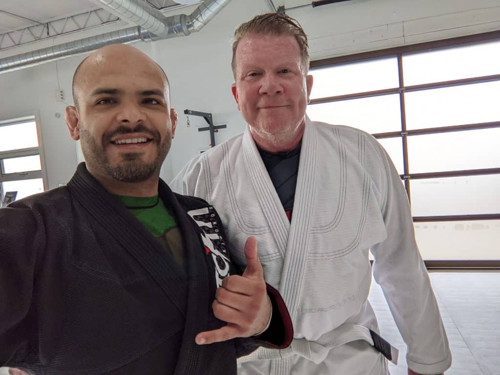 Two men in a gi and sweaty after having trained Brazilian Jiu Jitsu. The gentleman on the right is older.