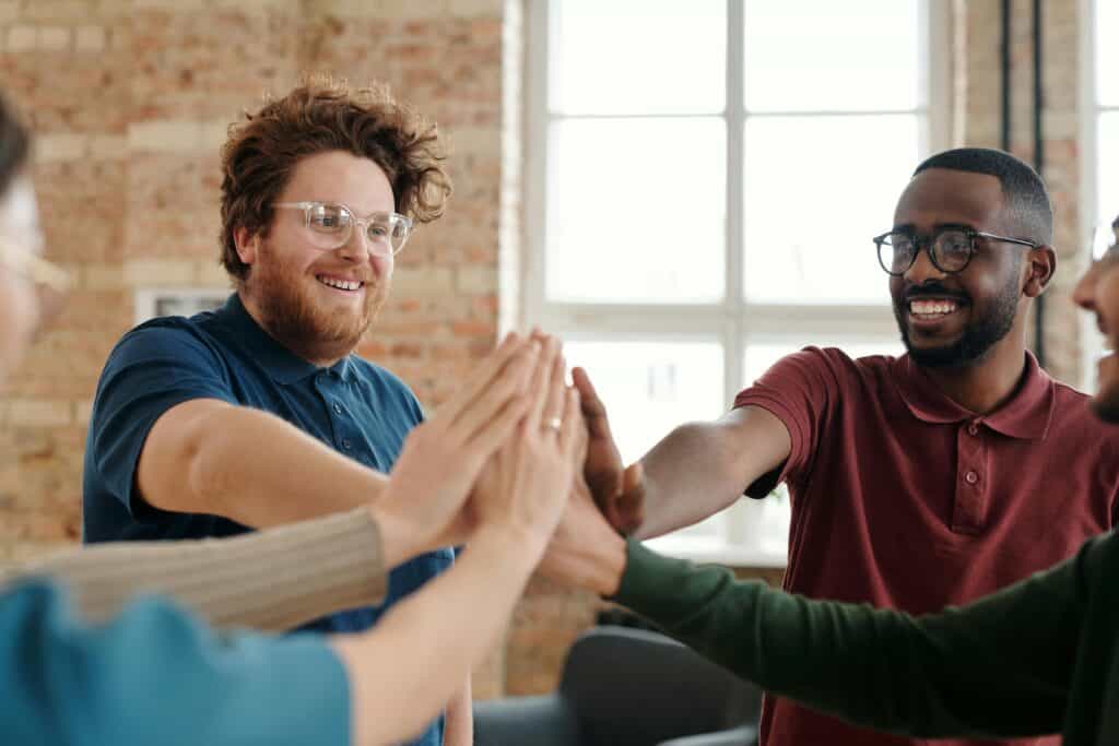 group of people all high fiving an imaginary center point for some reason